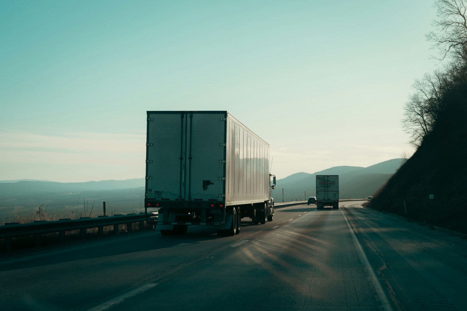 Two semi trucks traveling along a highway.