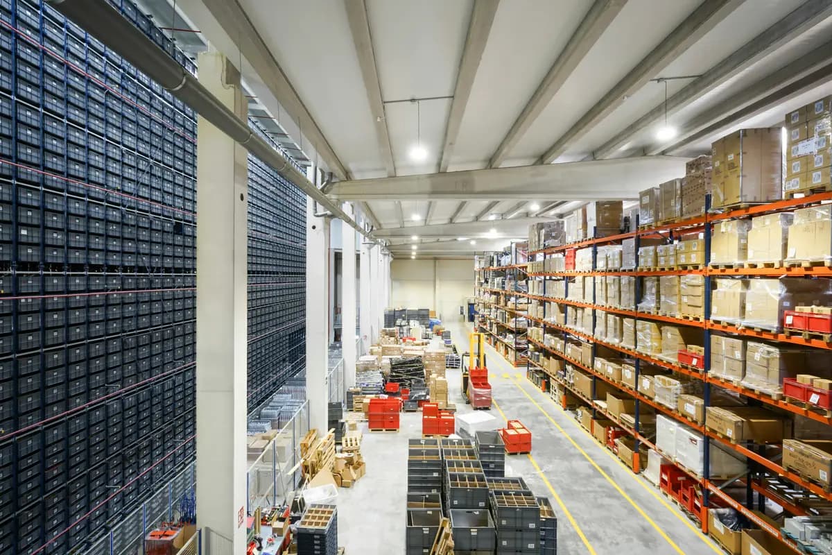 Tall warehouse storage racks filled with pallets and boxes beside a wide aisle.