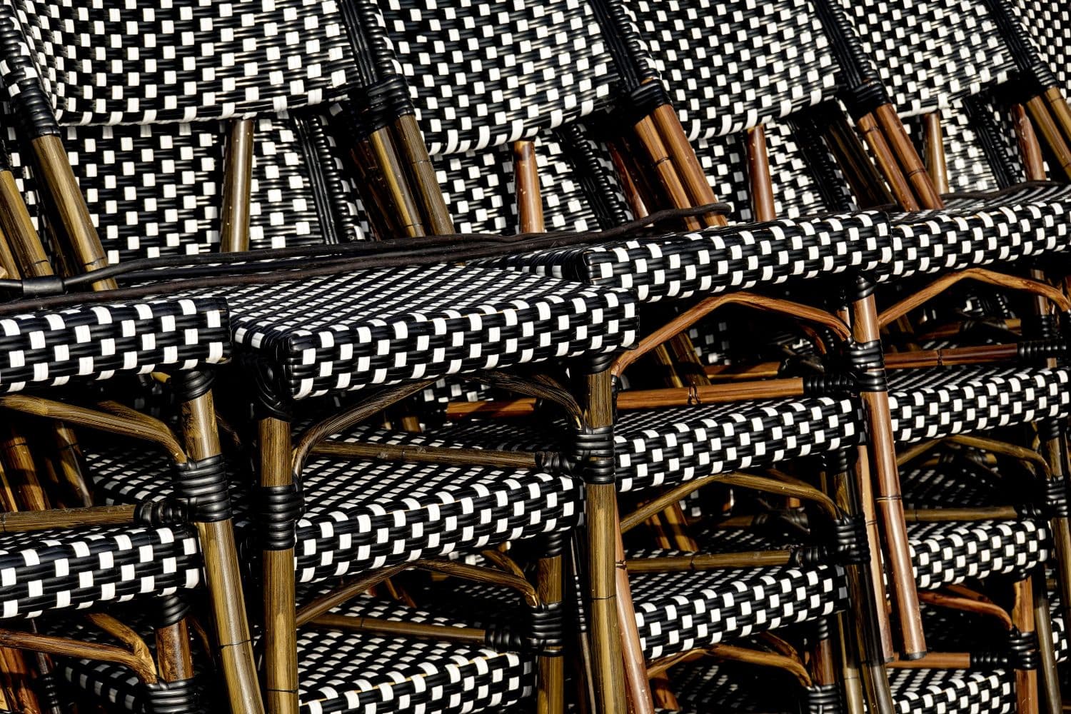 Stacked black-and-white woven patio chairs with wooden frames