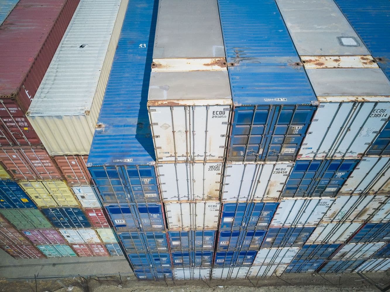 Aerial view of stacked shipping containers at a logistics facility.