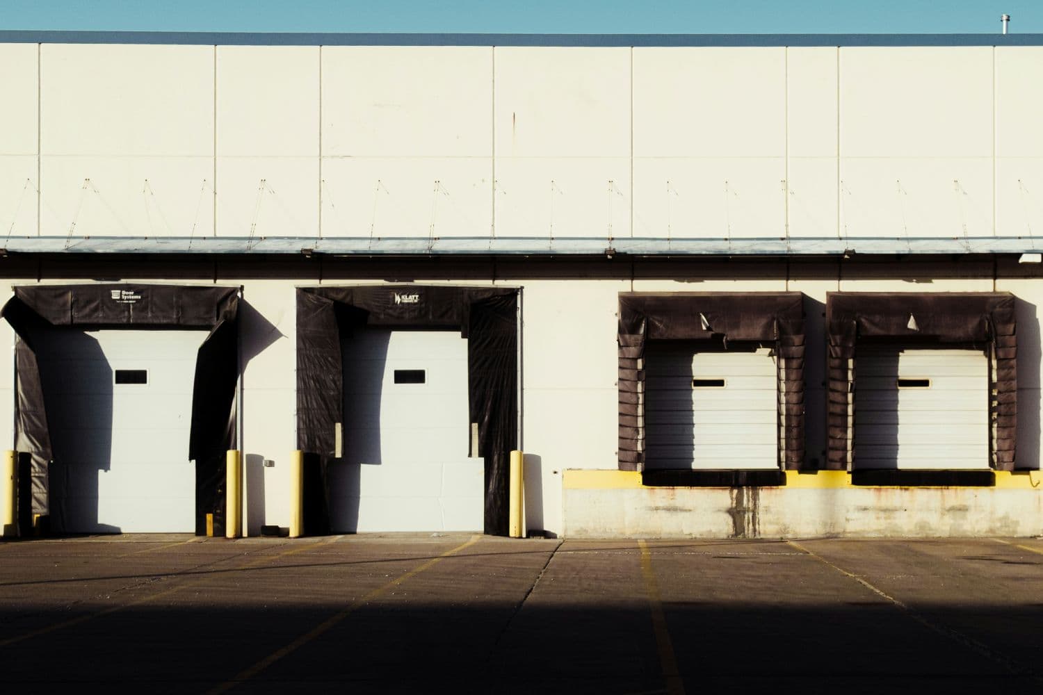 Exterior of a warehouse building featuring four loading dock doors.