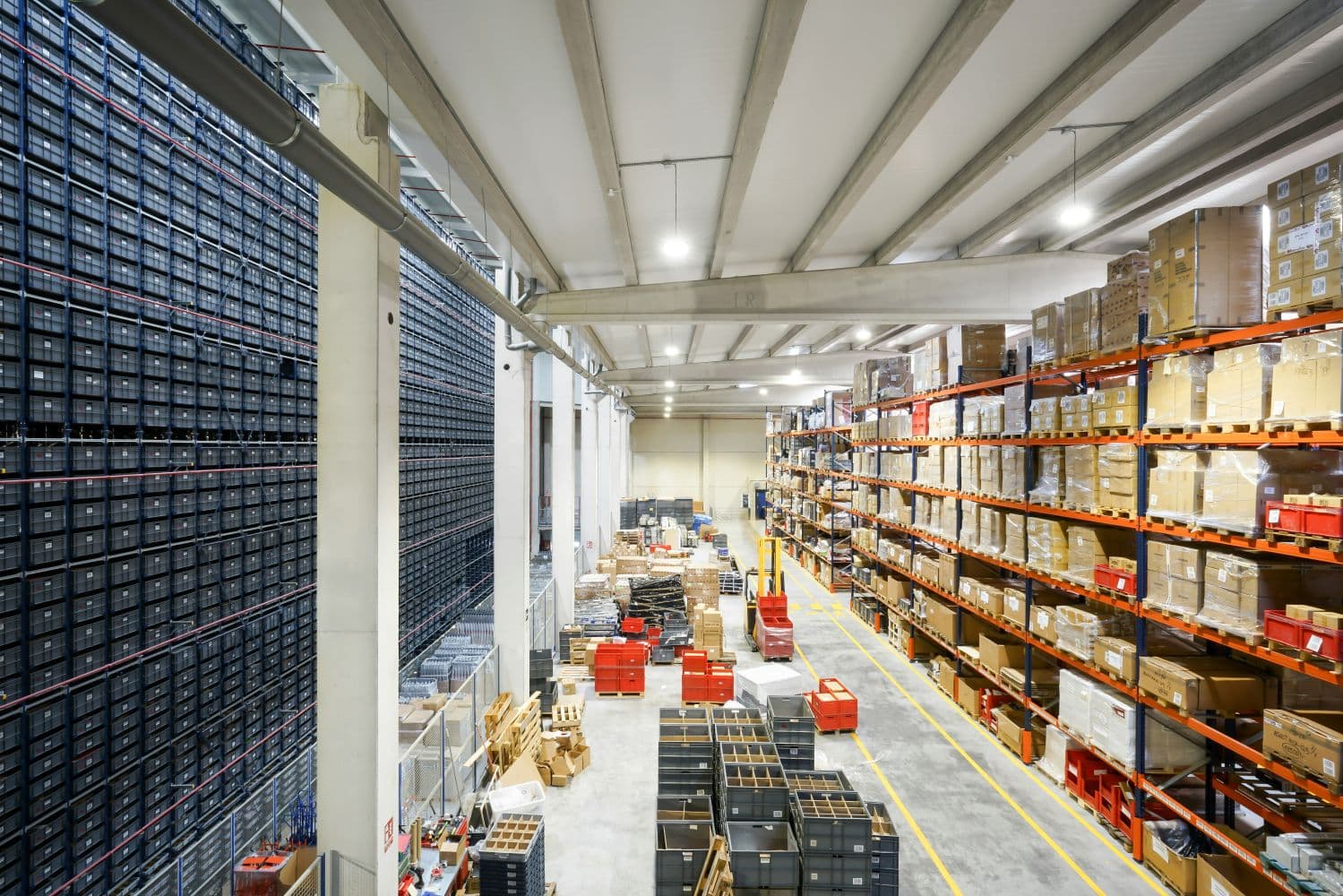 Wide overhead view of a warehouse with inventory storage racks, pallets, and organized aisles.
